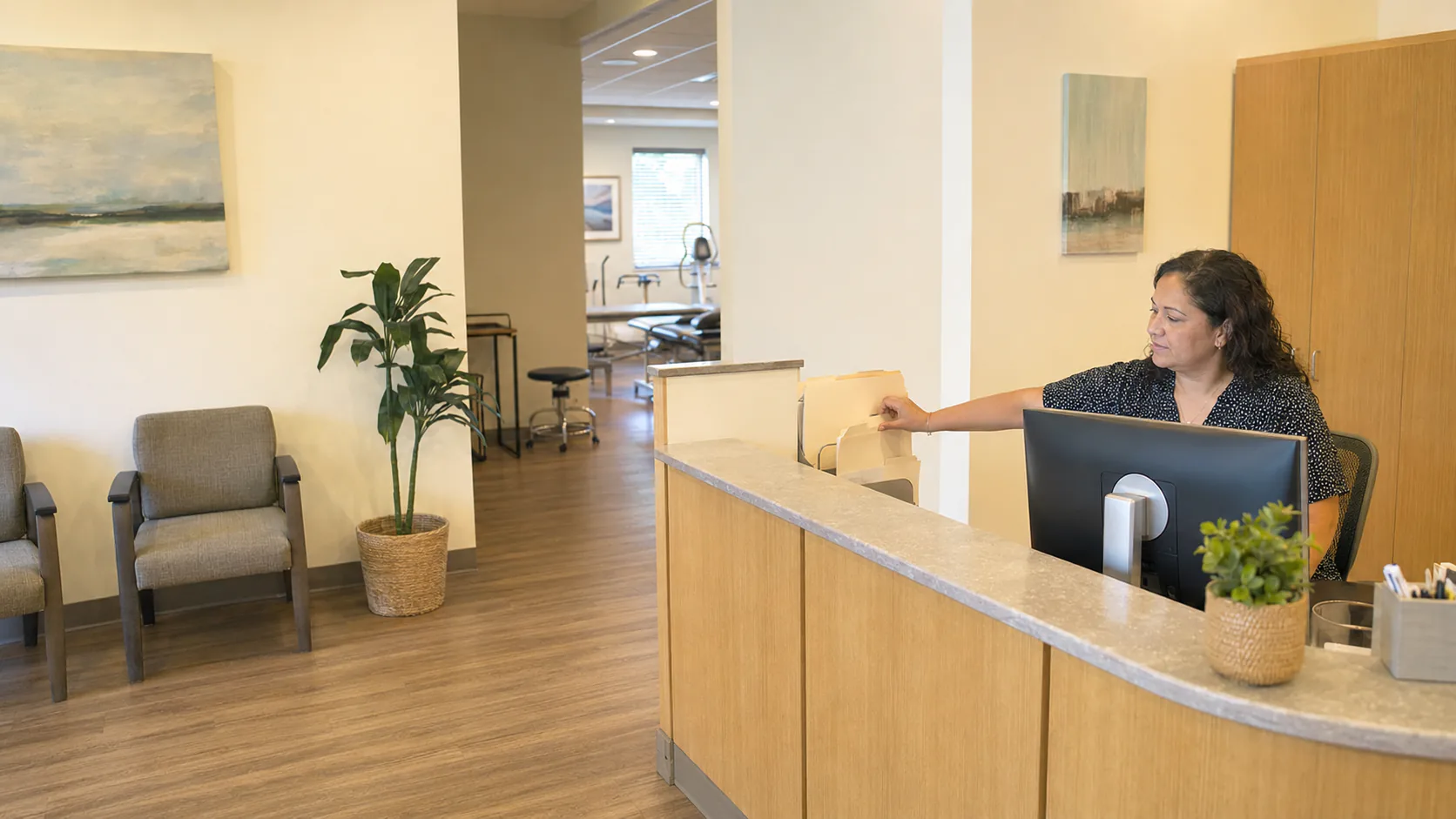 A clinic receptionist reaching for a patient document